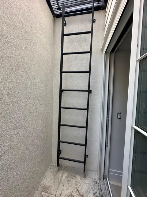 Vertical metal ladder beside a wall